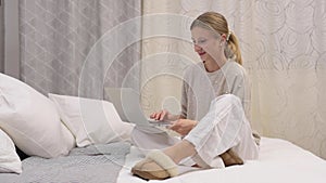 Beautiful woman is typing on her computer on bed