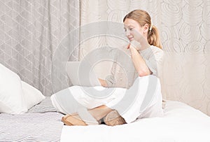 Beautiful woman is typing on her computer on bed