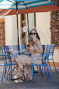 Beautiful woman typing a message in outdoor summer cafe