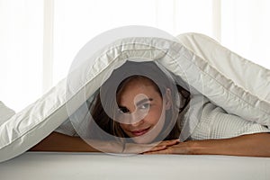 Beautiful woman under a white blanket on the bed