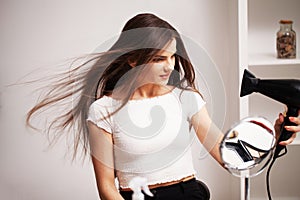 Beautiful woman uses a hair dryer to dry her hair after a shower