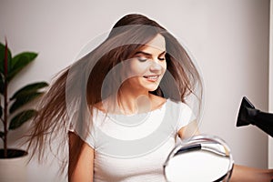 Beautiful woman uses a hair dryer to dry her hair after a shower