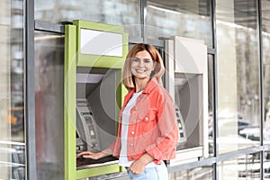 Beautiful woman using cash machine for money withdrawal
