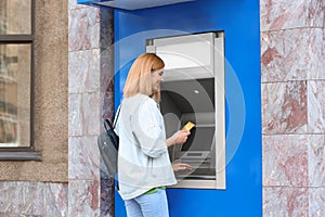 Beautiful woman using cash machine for money withdrawal