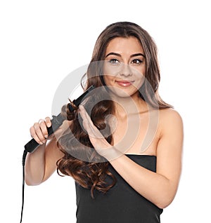 Beautiful woman using curler on her shiny wavy hair