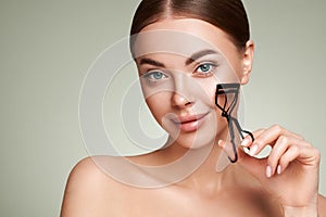 Beautiful woman using eyelash curler