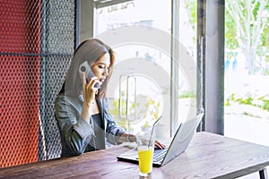 Beautiful woman using laptop and mobile phone in cafe