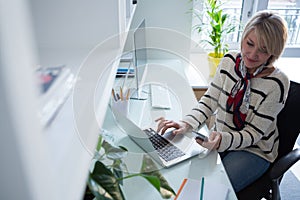 Woman using mobile phone and laptop at table