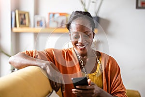 Beautiful woman using mobile phone while relaxing on sofa at home