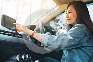 A beautiful woman using and pointing finger at navigation screen while driving car