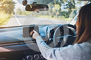 A beautiful woman using and pointing finger at navigation screen while driving car