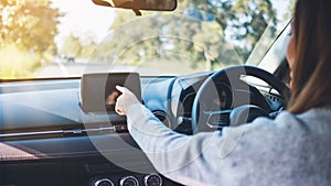 A beautiful woman using and pointing finger at navigation screen while driving car