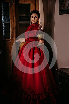 Beautiful woman in vintage 1800s early 1900s clothing red dress in old interior. Historical dresses, vintage outfits