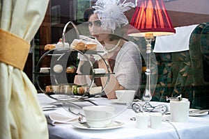 Beautiful woman in vintage clothing enjoying afternoon tea in train carriage