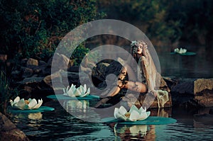 Beautiful woman in vintage dress sitting by the lake