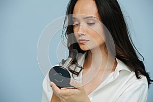 Beautiful woman with vitiligo looking in hand mirror, grooming