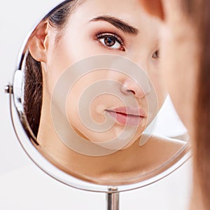 Beautiful woman with vitiligo looking in the mirror.
