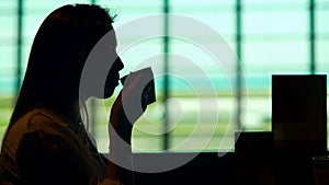 Beautiful woman waiting for plane at airport restaurant and drinking coffee