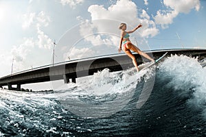 beautiful woman wakesurfer skilfully ride the wave on board at sunny summer day