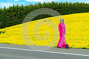 Beautiful women walking in amazing field of yellow rapeseed in the countryside. Canola oil plants