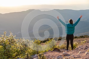 Beautiful woman walking on a path during sunset hands up