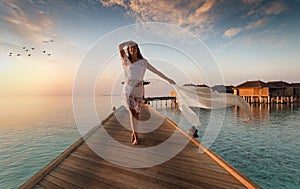 Beautiful woman walks down a wooden jetty on the Maldives