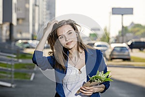 Beautiful woman walks through the streets listening to music on headphones with a bouquet