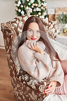 Beautiful woman in warm clothes on background of Christmas tree. Very beautiful girl smiling, closeup. Happy young lady near chris