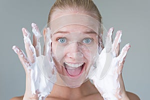 Beautiful woman washing her face with water and suds smiling. Hygiene and beauty skincare