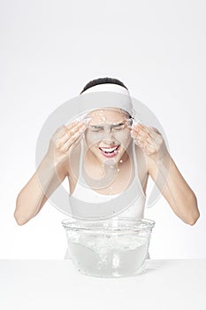 Beautiful woman is washing her face on white background