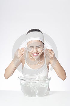 Beautiful woman is washing her face on white background