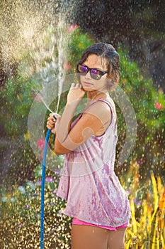 Beautiful woman watering roses with a garden hose