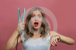 Beautiful woman with a wavy hair holding a hair iron