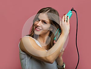 Beautiful woman with a wavy hair holding a hair iron