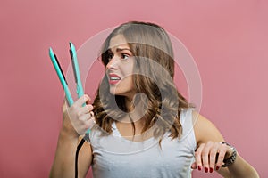 Beautiful woman with a wavy hair holding a hair iron