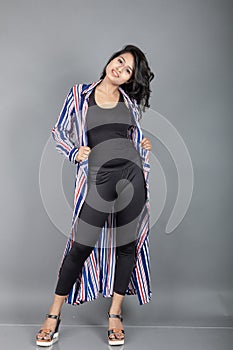 Beautiful woman wearing black leggings, black top and red, blue, white striped tunic. Female model in casual wear, advertisement