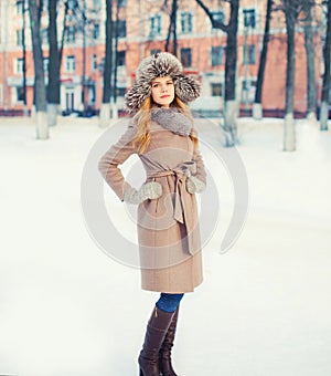 Beautiful woman wearing a coat jacket and hat over snow in winter