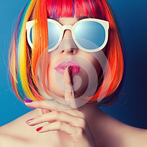 beautiful woman wearing colorful wig and white sunglasses agains