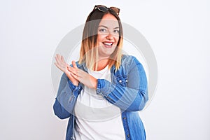 Beautiful woman wearing denim shirt standing over isolated white background clapping and applauding happy and joyful, smiling