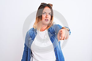 Beautiful woman wearing denim shirt standing over isolated white background pointing displeased and frustrated to the camera,
