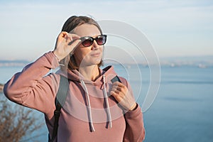 Beautiful woman wearing eyeglasses looking on the sunlight over the sea background