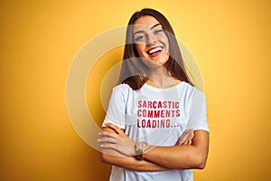 Beautiful woman wearing fanny t-shirt with irony comments over isolated yellow background happy face smiling with crossed arms