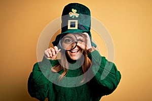 Beautiful woman wearing green hat holding magnifying glass on saint patricks day celebration with happy face smiling doing ok sign