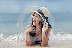 Beautiful woman wearing a hat lying on the beach