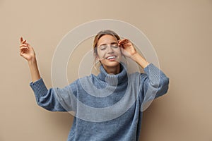 Beautiful woman wearing knitted sweater on beige background