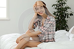 Beautiful woman wearing pajamas and sleep mask indoors. Bedtime