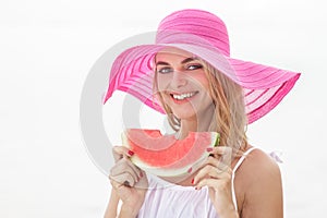 beautiful woman wearing pink sunhat smiling and eating watermelon