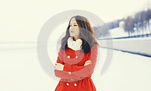 Beautiful woman wearing a red coat and scarf over snow in winter