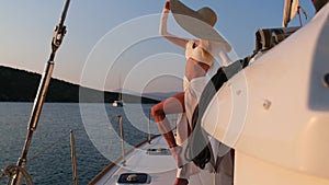 Beautiful woman wearing straw hat and white dress on a yacht enjoys the journey, Spetses, Greece, Europe