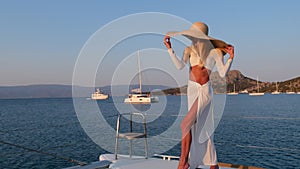 Beautiful woman wearing straw hat and white dress on a yacht enjoys the journey, Spetses, Greece, Europe